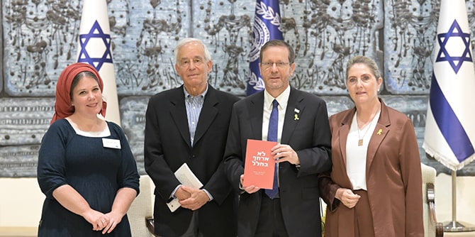 The President standing and holding the book with his wife on one side and Mandel president and graduate on the other